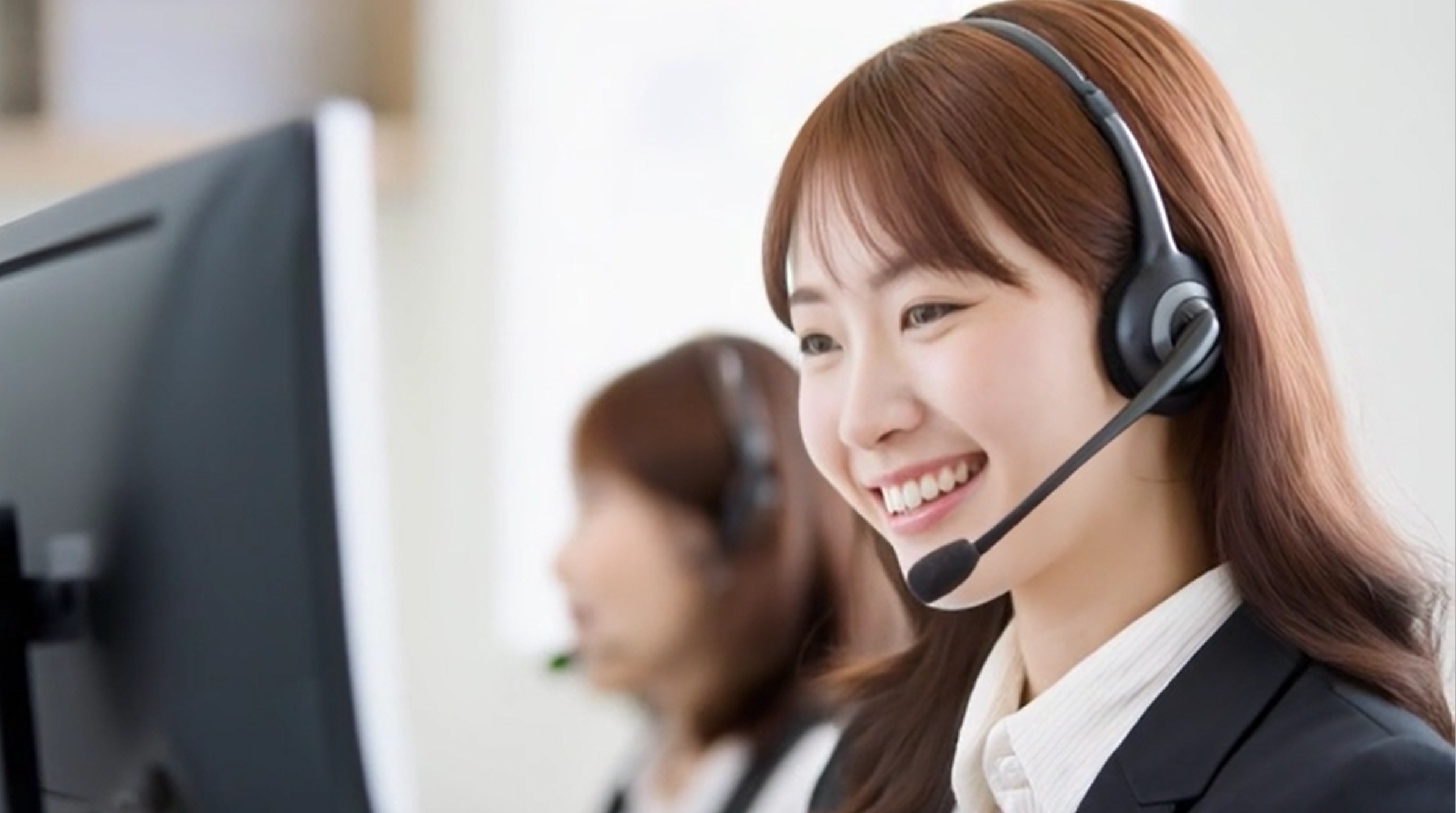 探偵への無料相談窓口で、ヘッドセットを付けたスタッフが笑顔で対応している様子